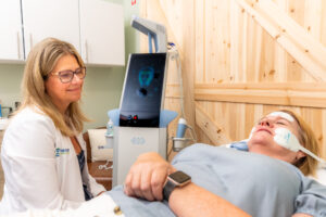 Woman laying down in med spa office receiving noninvasive facelift near Newport, RI