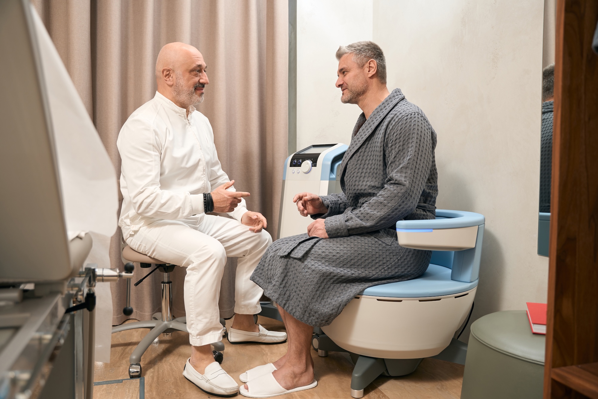 A male patient talking to a male provider at Harbour Direct Primary Care about what to expect before beginning using Emsella for urinary incontinence treatment in Jamestown, RI.